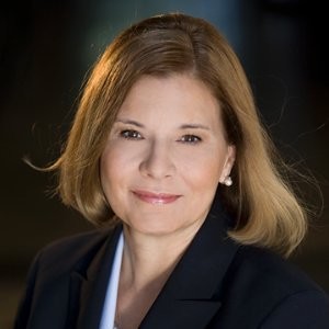 The professional photo of the female county attorney. She is smiling with light brown. chin length hair, hazel eyes, gold studded earrings and a black business jacket with crisp white shirt.